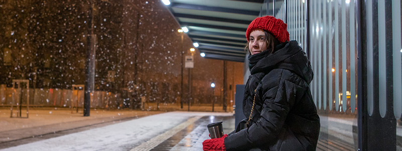 Osallisuus. Henkilö yksinään istumassa pysäkillä.